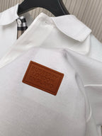 Brown leather-style logo patch on white polo shirt placket