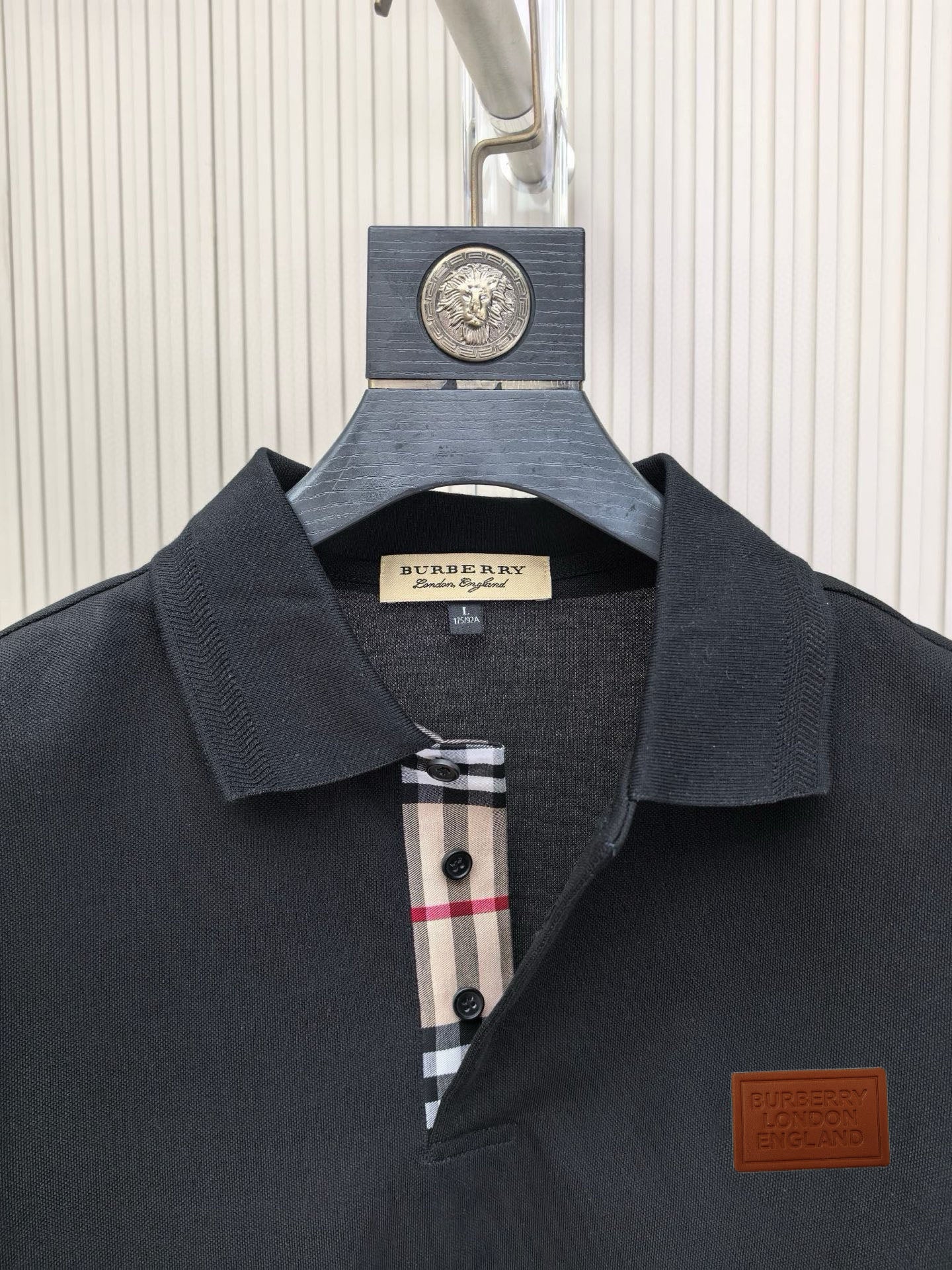 Dark polo shirt collar with button placket and check inner trim, logo patch