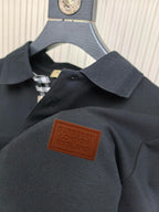 Dark polo shirt chest area with brown logo patch on textured fabric