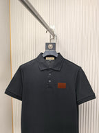 Black polo shirt on hanger with short sleeves and chest logo patch