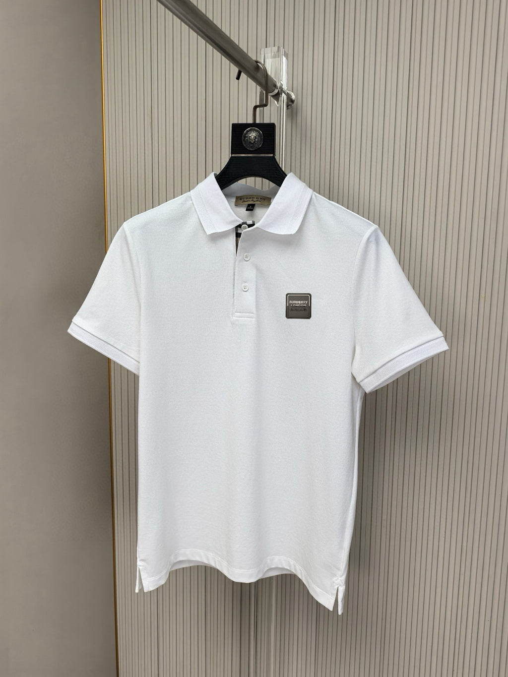 White polo shirt on hanger, buttoned collar and small chest logo patch