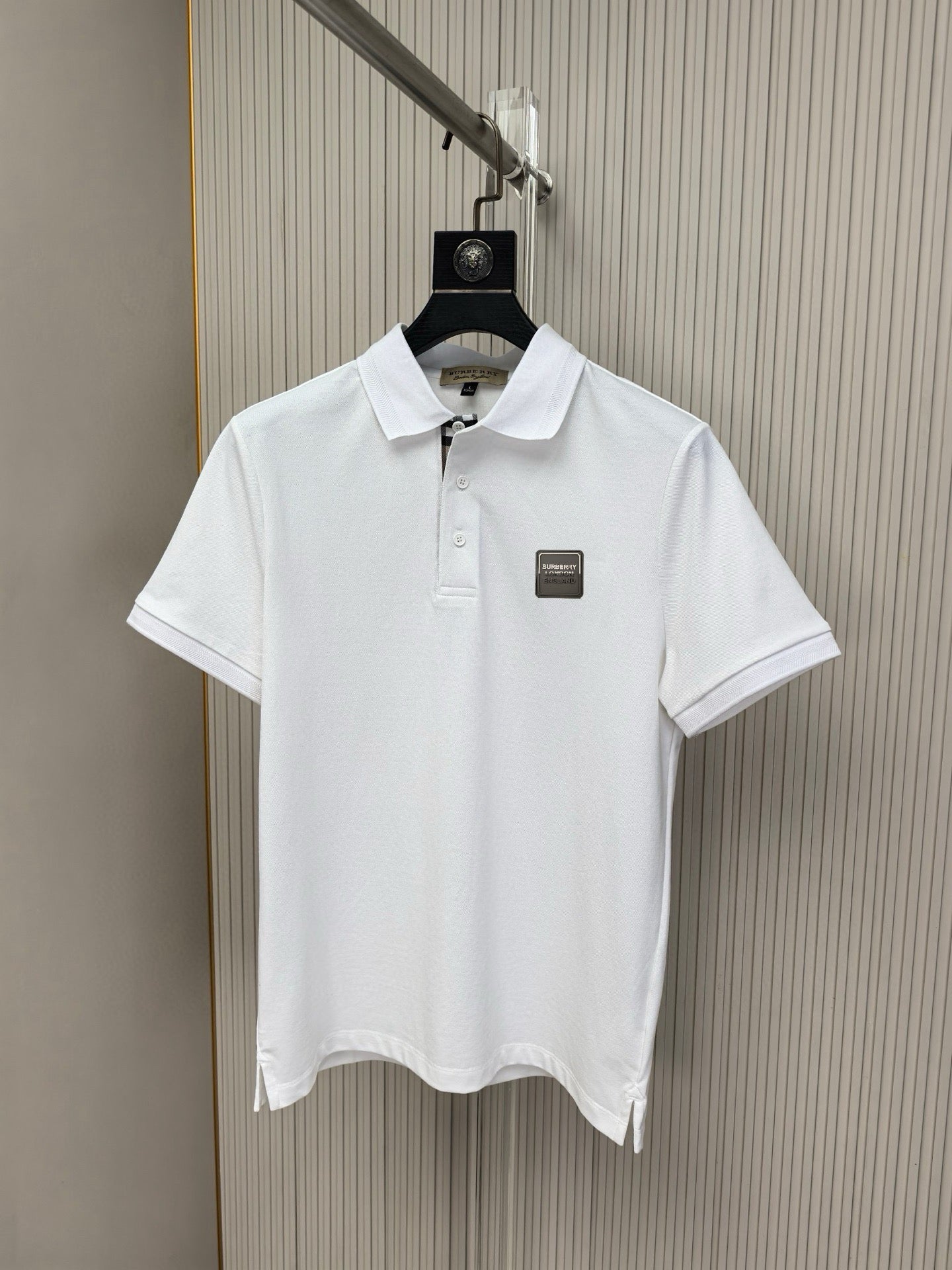 White polo shirt on hanger, buttoned collar and small chest logo patch