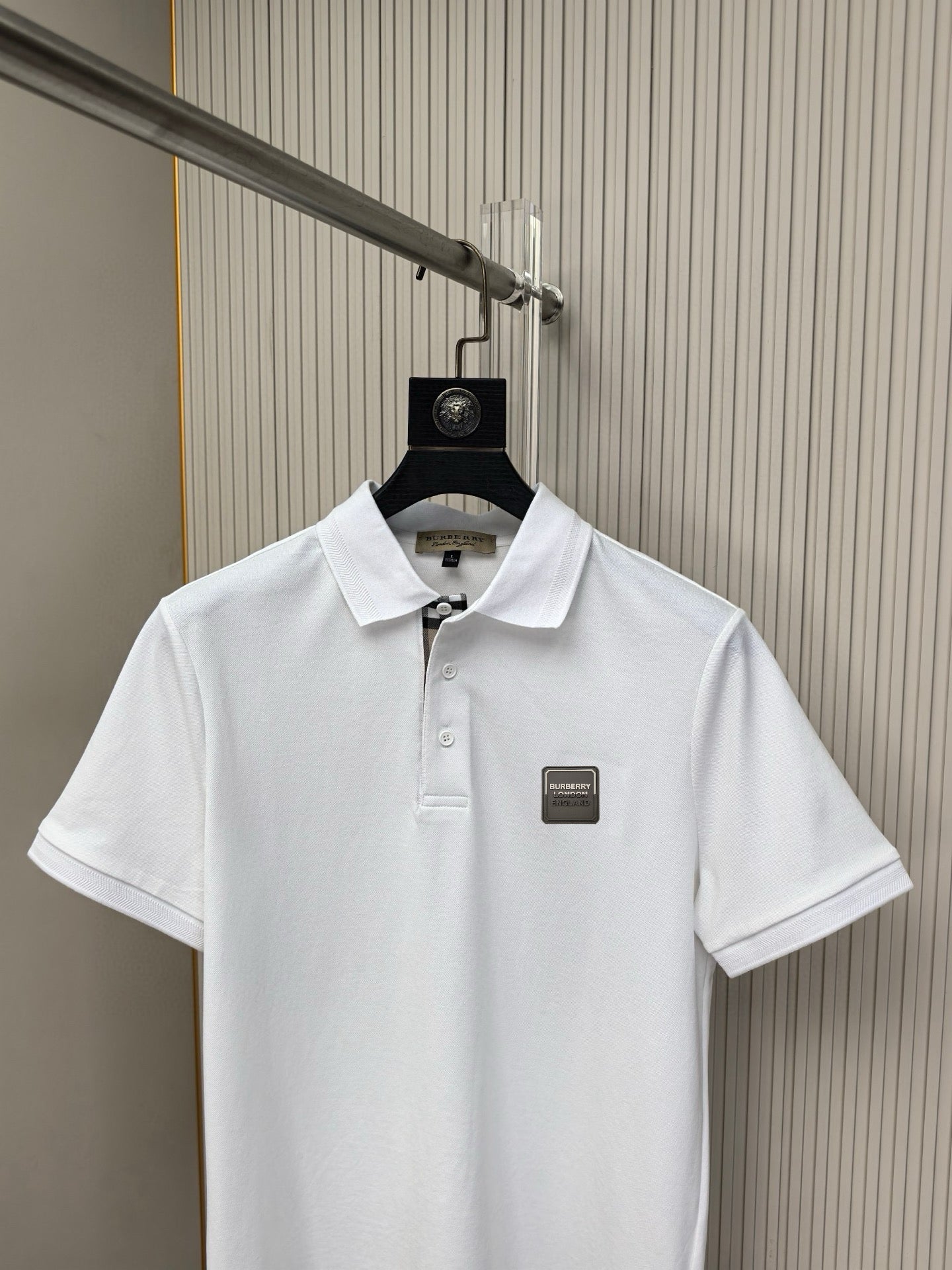 White polo shirt on hanger, buttoned placket and chest logo patch