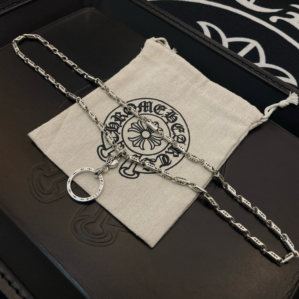 Silver tone chain necklace with round hoop pendant on a light drawstring pouch.