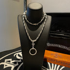 Silver tone chain necklace with round hoop pendant and clasp links, on a bust stand.