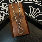 Silver tone chain necklace with round hoop pendant hanging over a wooden display block.