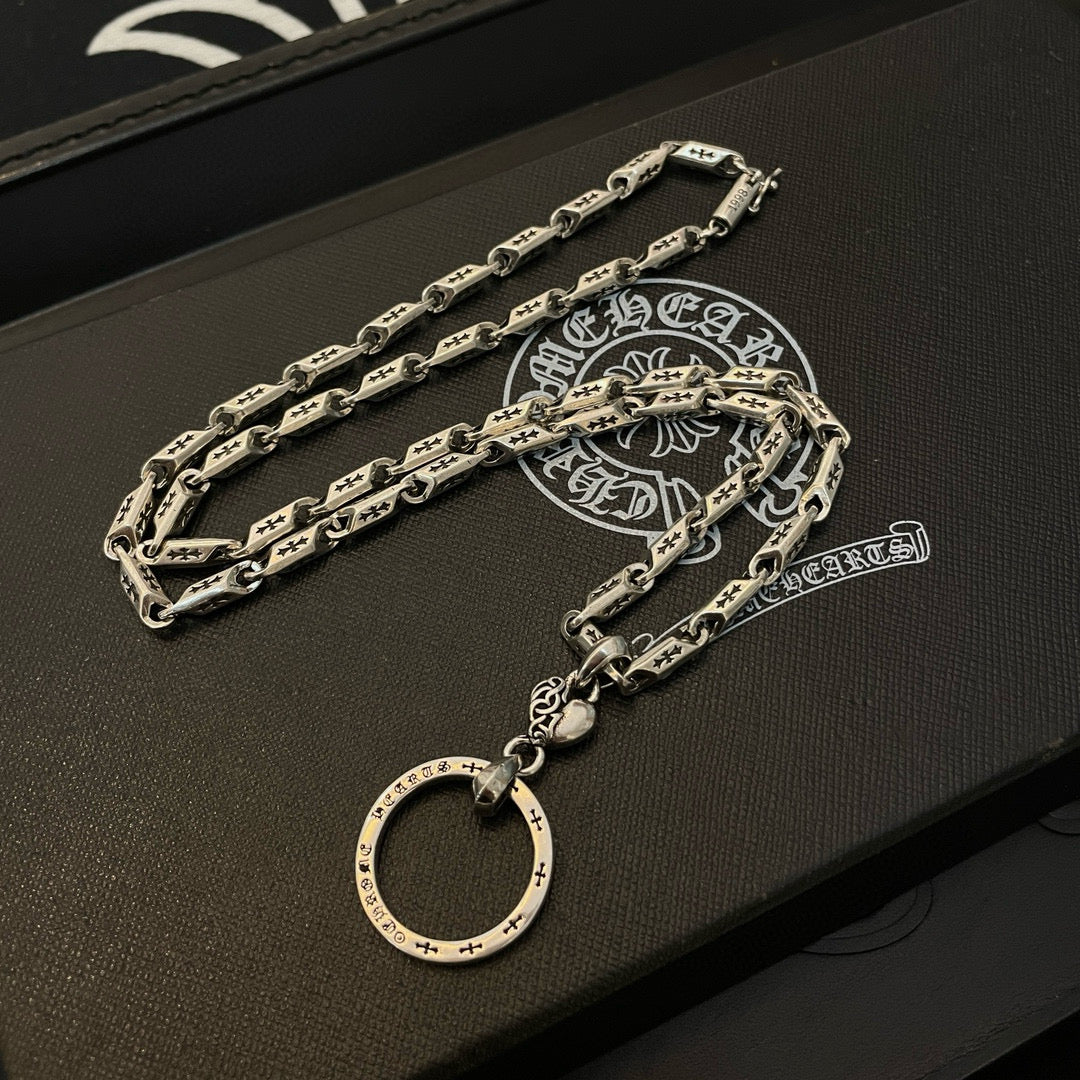 Silver tone chain necklace with round hoop pendant on a black jewelry box insert.