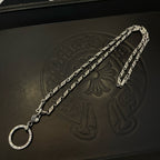 Silver tone chain necklace with round hoop pendant, laid out on dark leather surface.