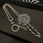 Silver tone chain necklace set on a black box surface, with round hoop pendant.