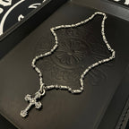 Silver-toned beaded chain cross pendant necklace on black embossed tray
