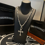 Silver-toned cross pendant necklace displayed on black bust with chain links