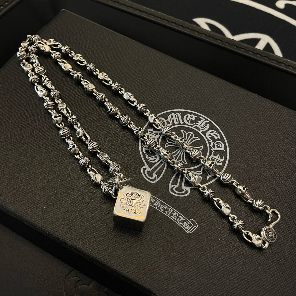 Silver-tone chain bracelet set with square and star-like charms on a dark tray
