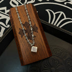 Silver tone chain necklace with square pendant on wood accessory holder