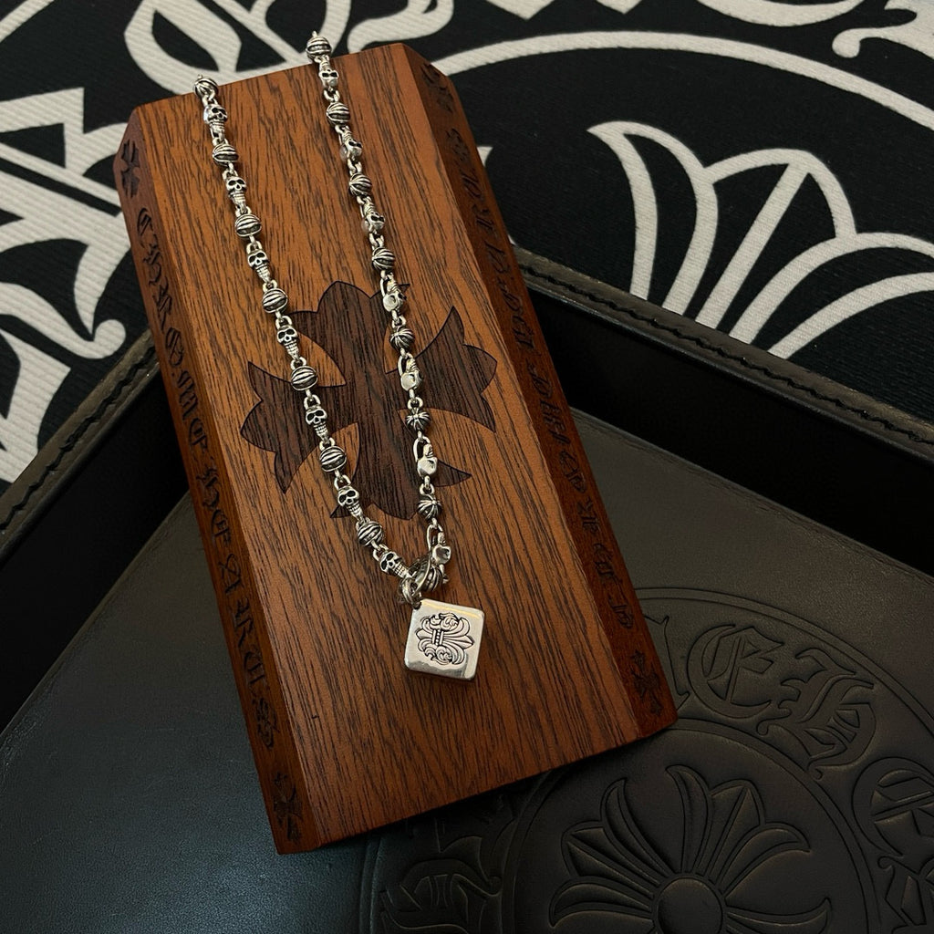 Silver-tone chain necklaces with square pendant on a wooden display stand