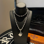 Double silver tone chain necklace with star-like charm and pendant on stand