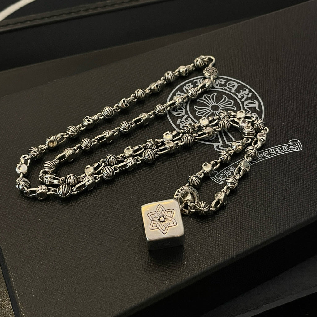 Silver tone chain necklace with teardrop pendant charms on dark display box