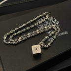 Silver tone chain necklace with teardrop pendant charms on dark display box
