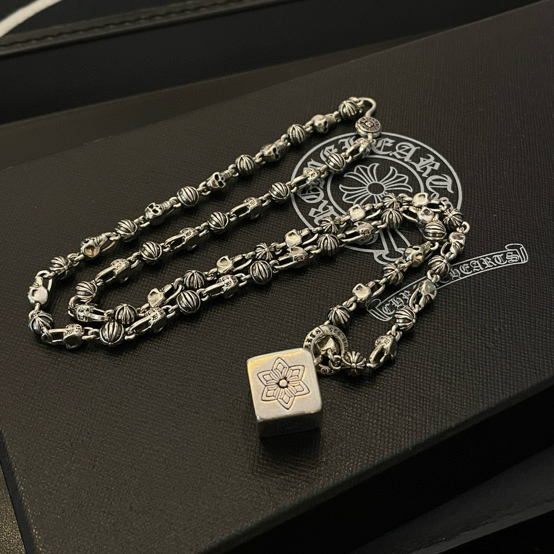 Silver tone chain necklace with teardrop pendant charms on dark display box