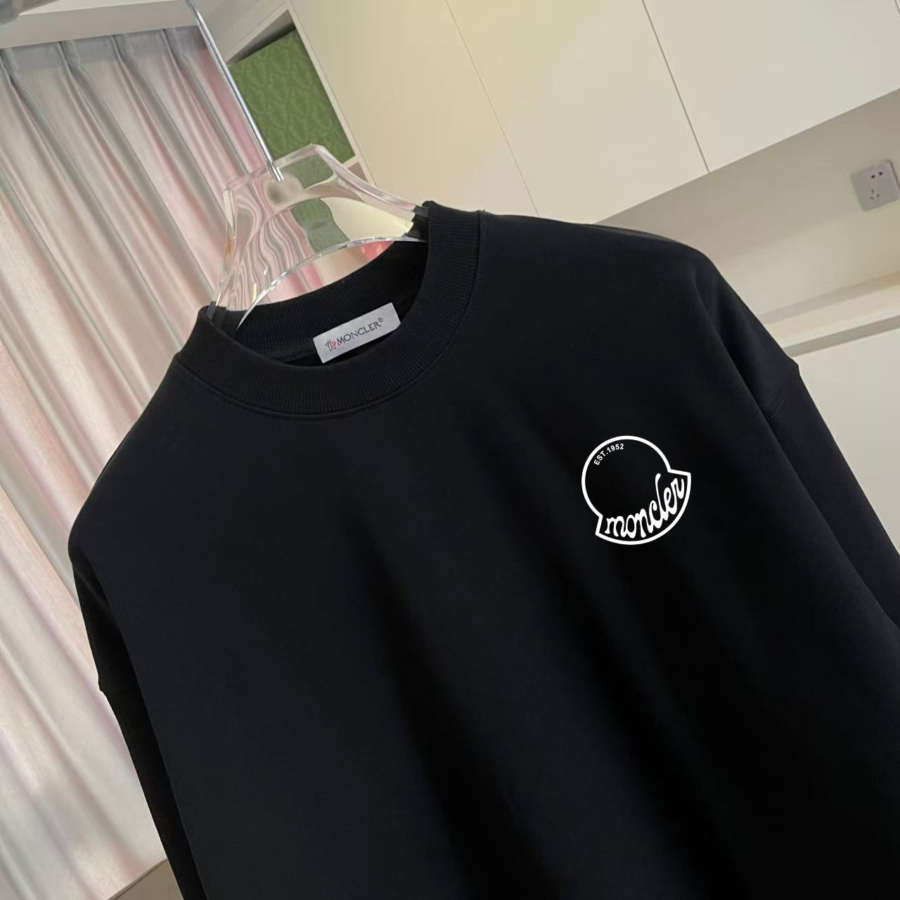 Black sweatshirt close-up with round Moncler logo on upper chest