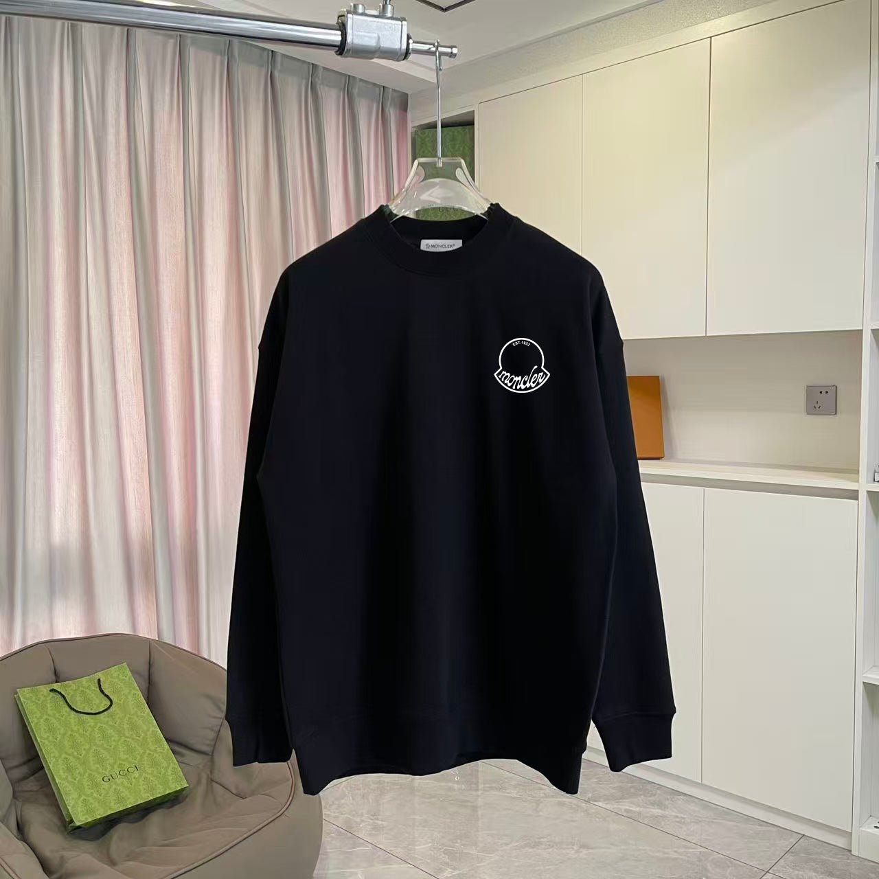 Black long-sleeve sweatshirt with small circular Moncler logo on chest