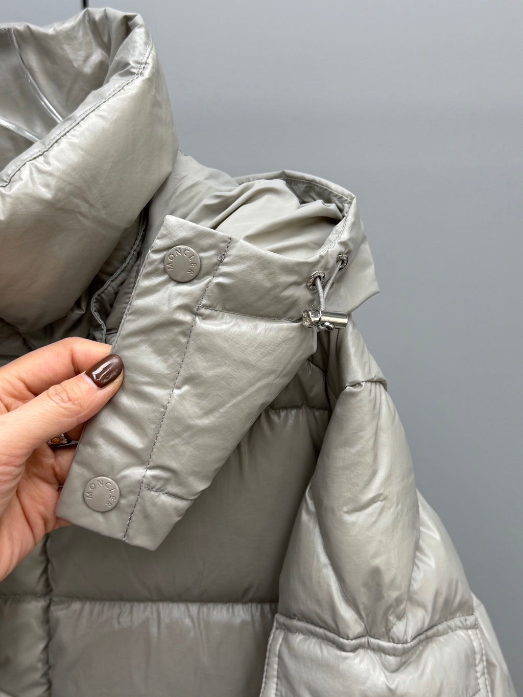 Light gray puffer jacket detail with snap buttons and textured fabric quilting