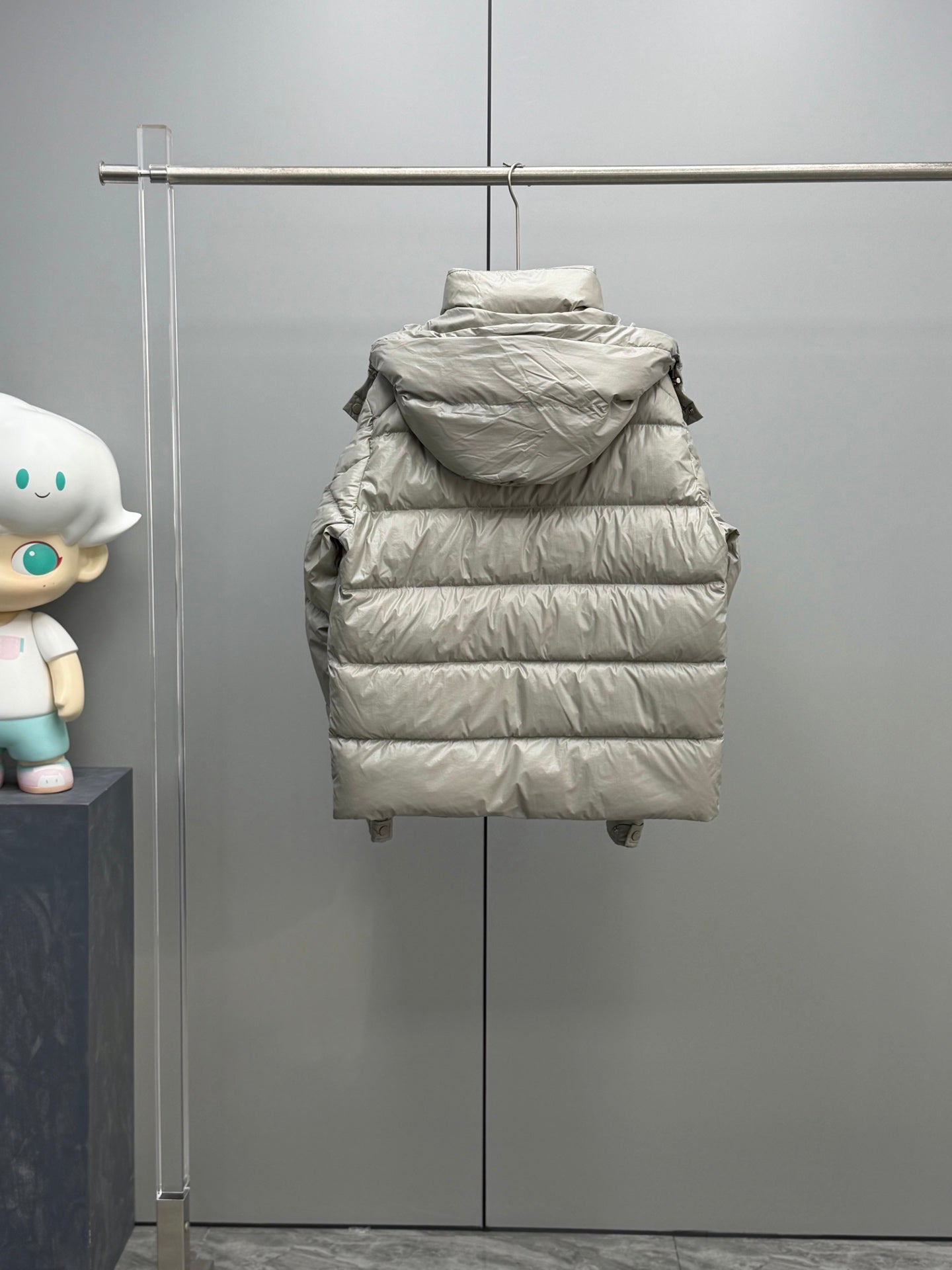 Light gray hooded puffer jacket front view on display, with full-length quilted panels