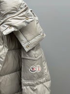 Light gray puffer jacket sleeve and chest pocket with snap buttons and logo patch