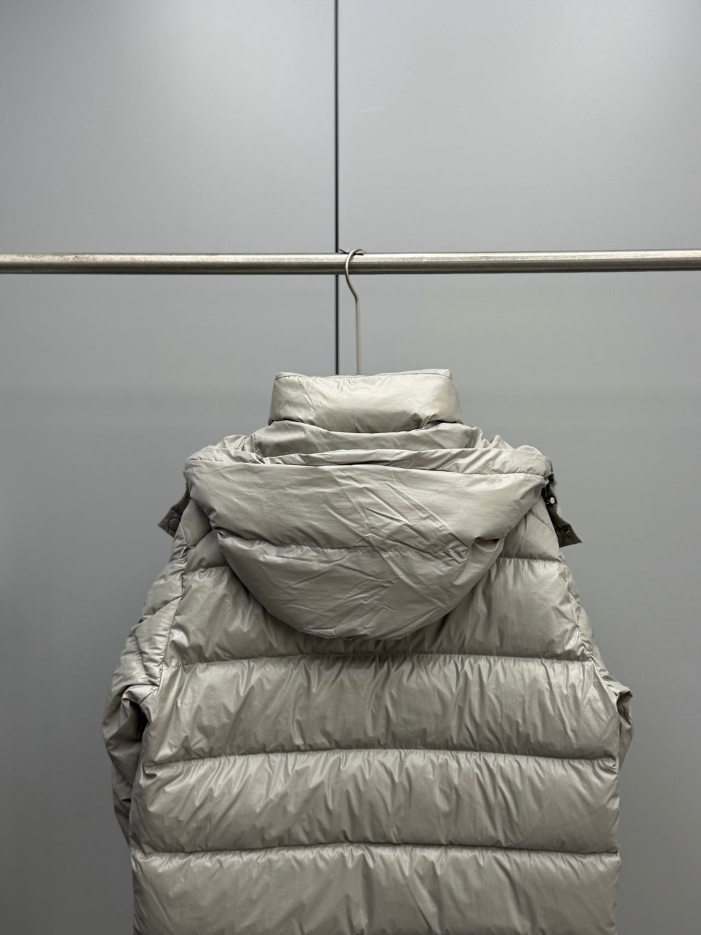 Light gray hooded puffer jacket back view with quilted stripes and zipper