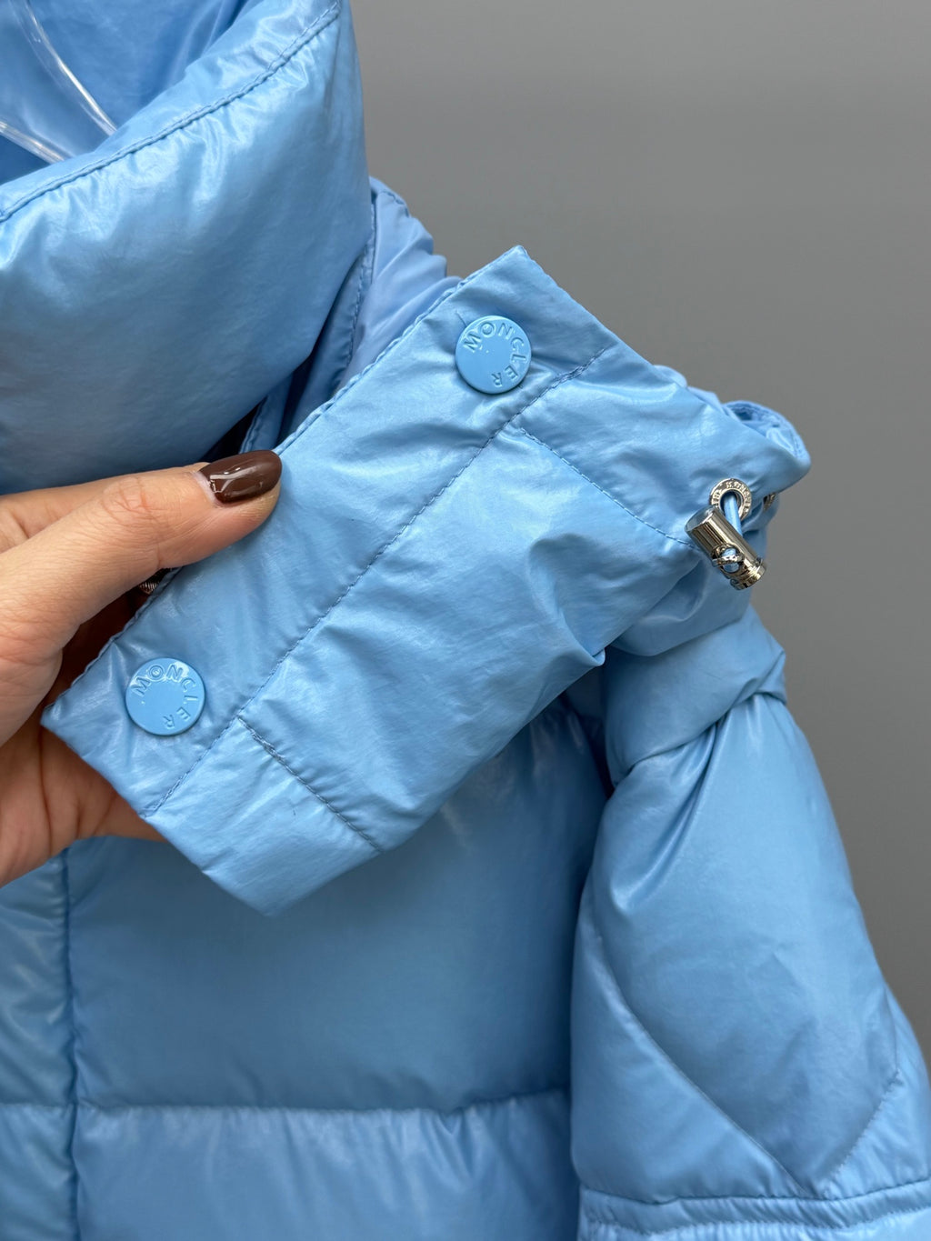 Moncler light blue puffer jacket, close-up of snap button and shoulder