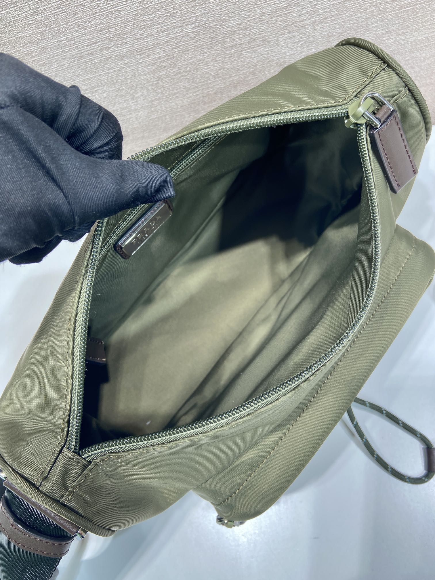Olive Prada bag with open top zipper and fabric-lined interior