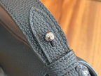 Black Dior leather bag strap end with circular logo snap detail.