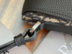 Black Dior bag with patterned trim and silver clasp near the zipper.