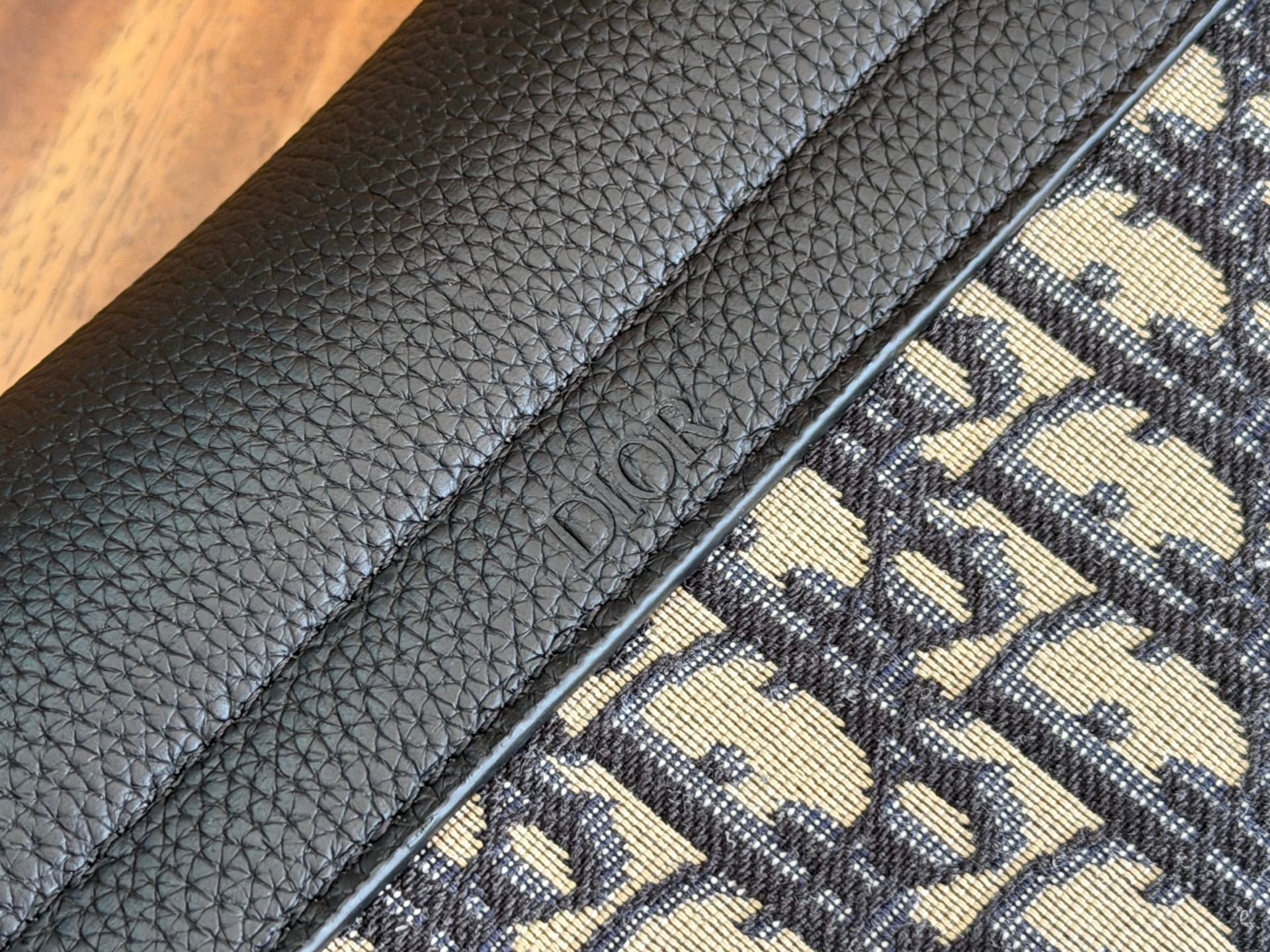 Black Dior leather panel with embossed Dior text on textured strap.