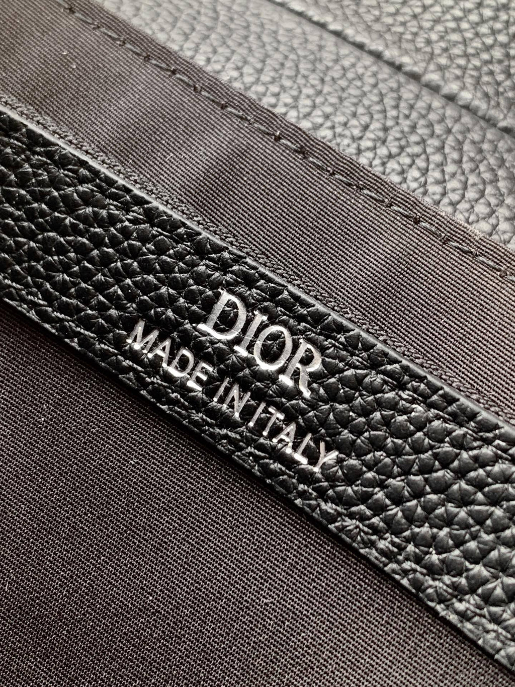 Black Dior leather label reading “DIOR” and “MADE IN ITALY” on edge seam.
