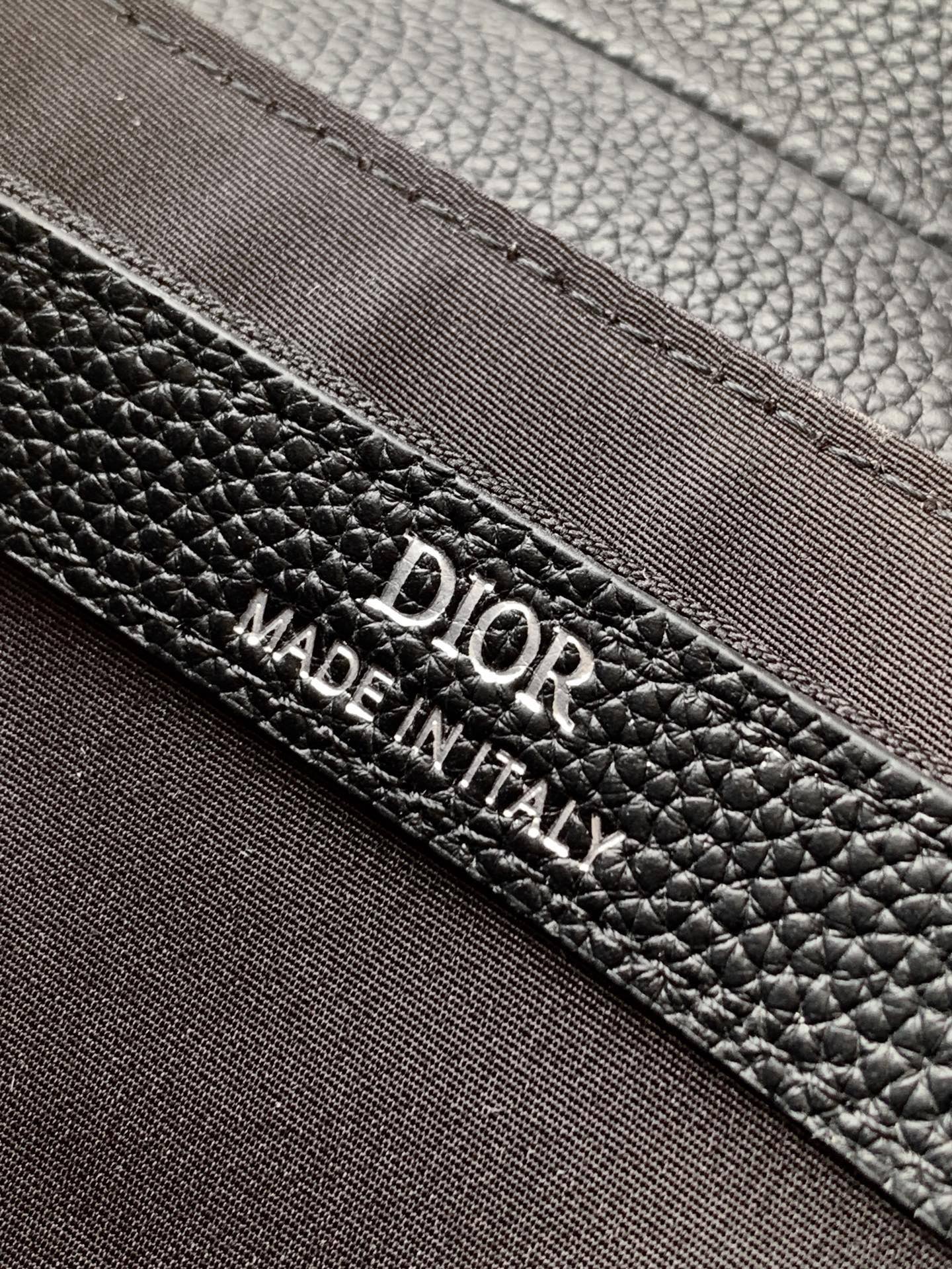 Black Dior leather label reading “DIOR” and “MADE IN ITALY” on edge seam.