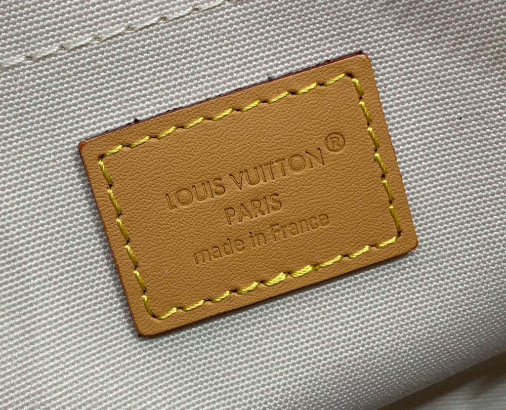 Louis Vuitton leather brand patch stitched on beige canvas