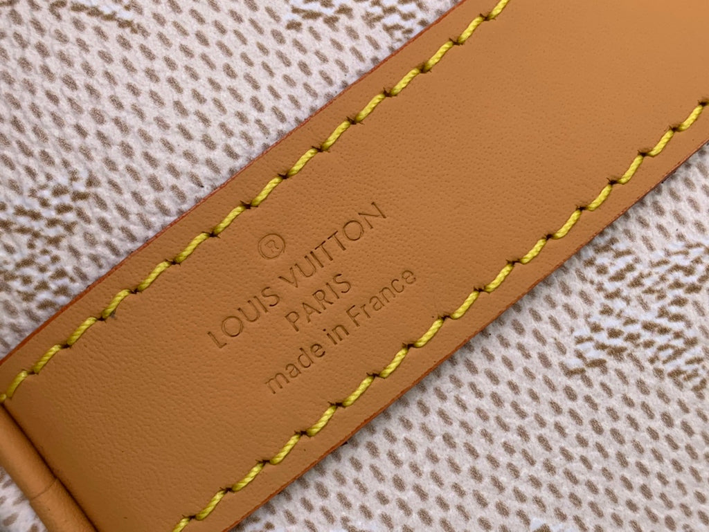 Louis Vuitton leather label on tan edge, stitched over beige fabric