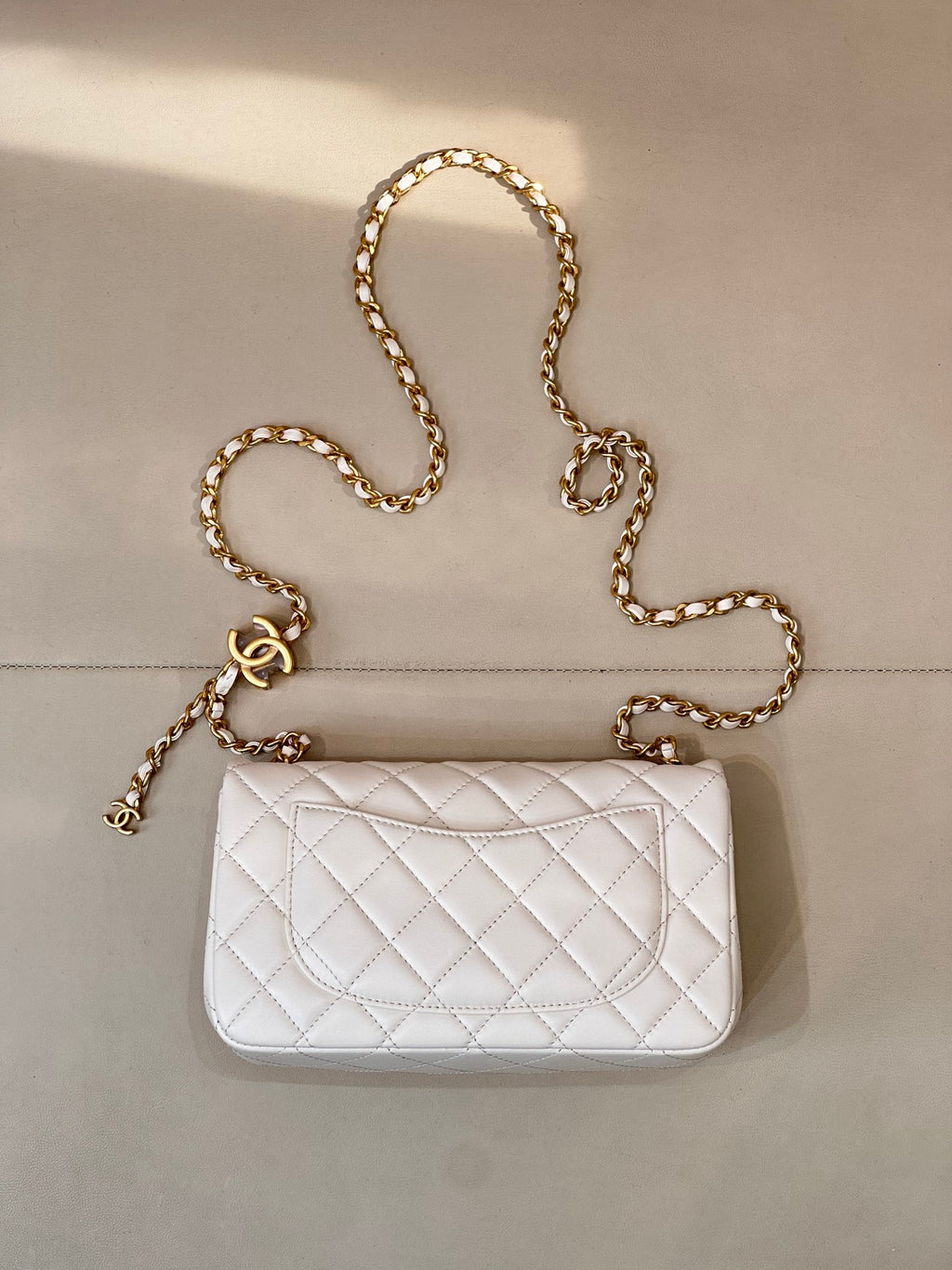 White quilted Chanel flap bag with gold chain strap and CC logo front.