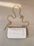 White quilted Chanel flap bag with gold chain strap and CC logo front.