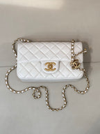 White quilted Chanel shoulder bag with gold chain strap and CC logo front panel.