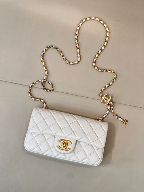 White quilted Chanel flap bag with gold-tone chain strap and CC emblem on front.