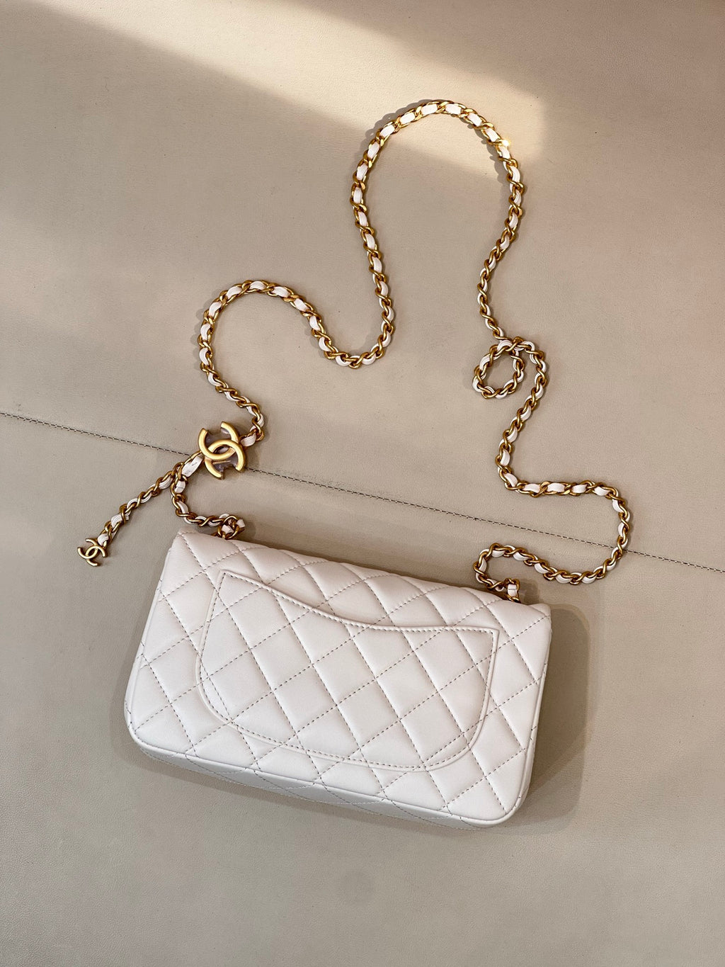 White quilted Chanel flap bag with gold chain shoulder strap and CC logo front.