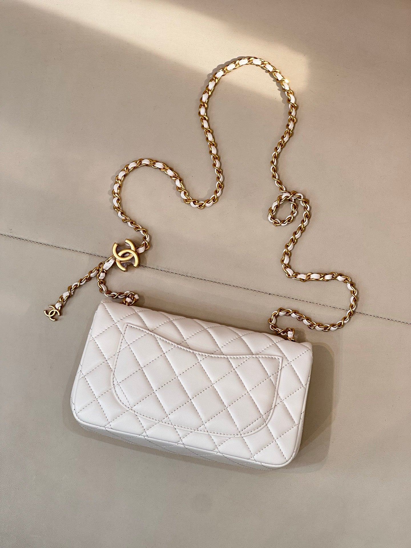 White quilted Chanel flap bag with gold chain shoulder strap and CC logo front.