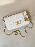 White quilted Chanel flap bag with gold chain crossbody strap and CC logo clasp.