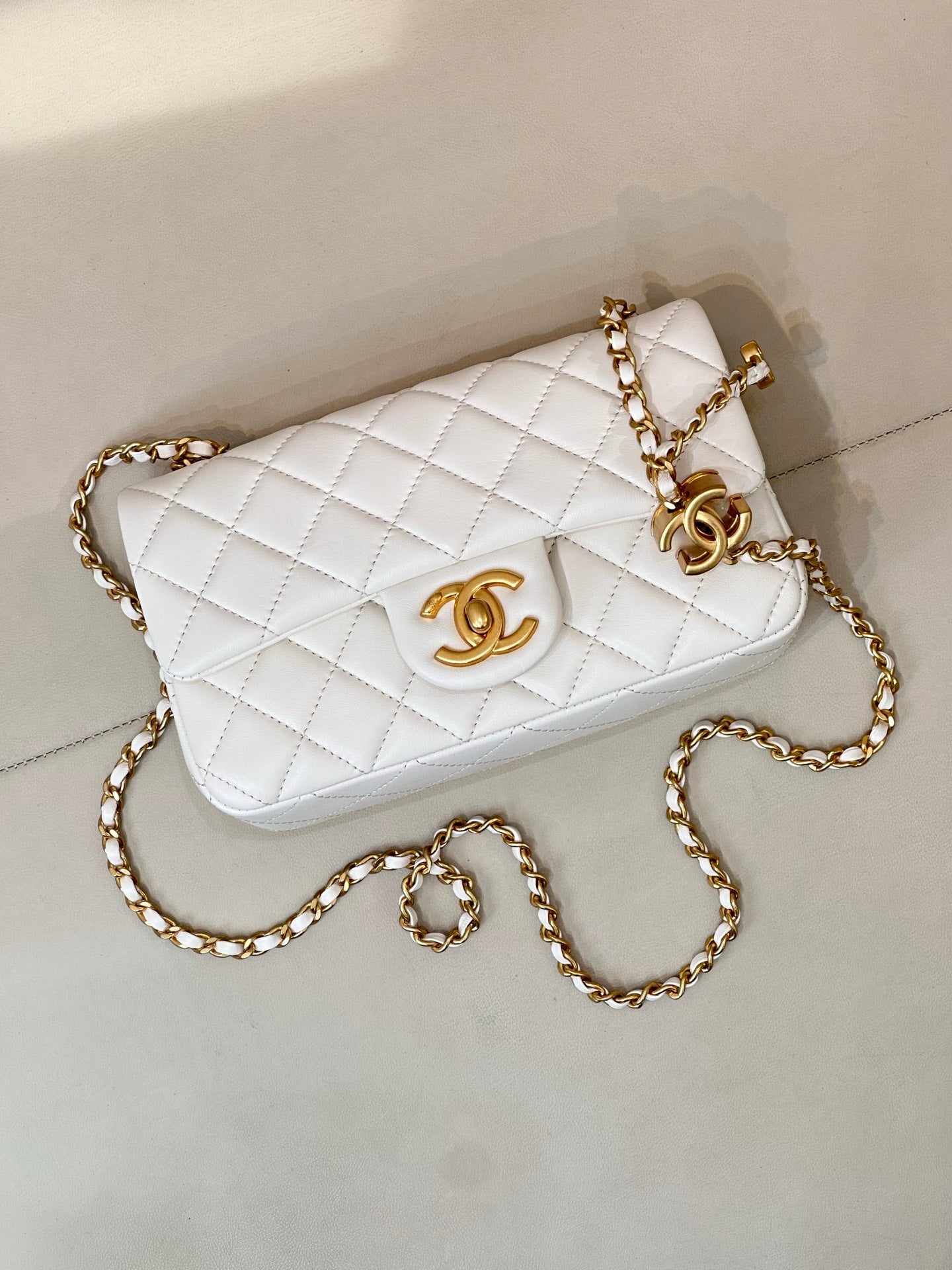 White quilted Chanel flap bag with gold chain crossbody strap and CC logo clasp.