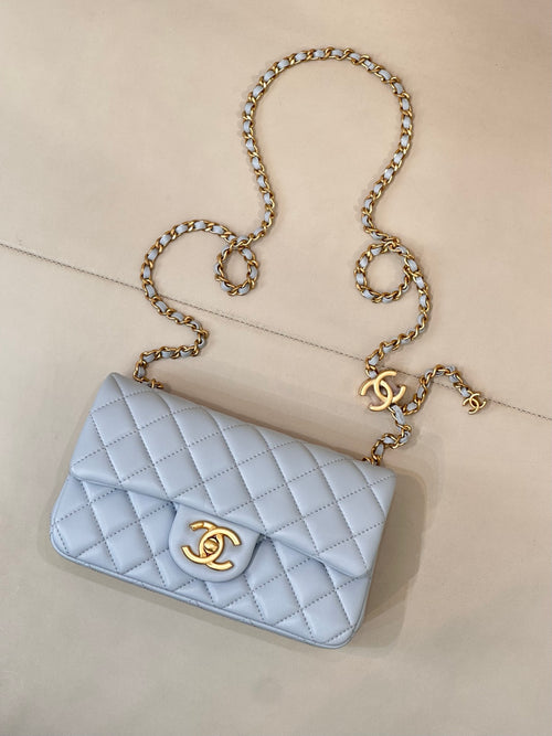 Light blue quilted shoulder bag with gold chain strap and gold logo on flap