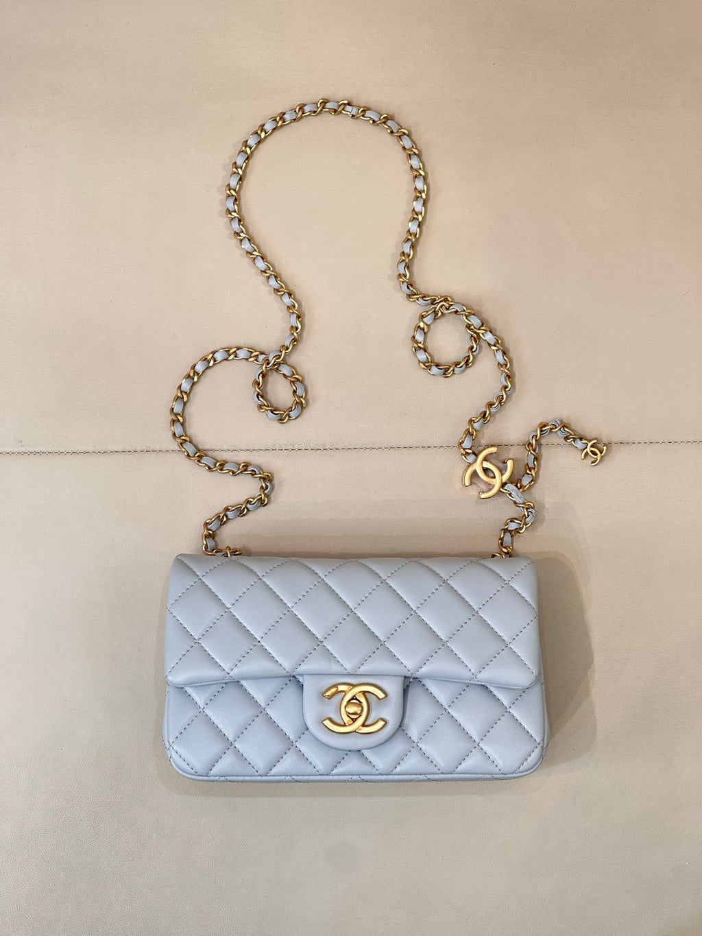 Light blue quilted flap shoulder bag with gold chain and gold logo medallion