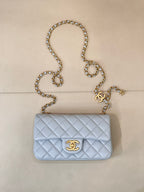 Light blue quilted flap shoulder bag with gold chain and gold logo medallion