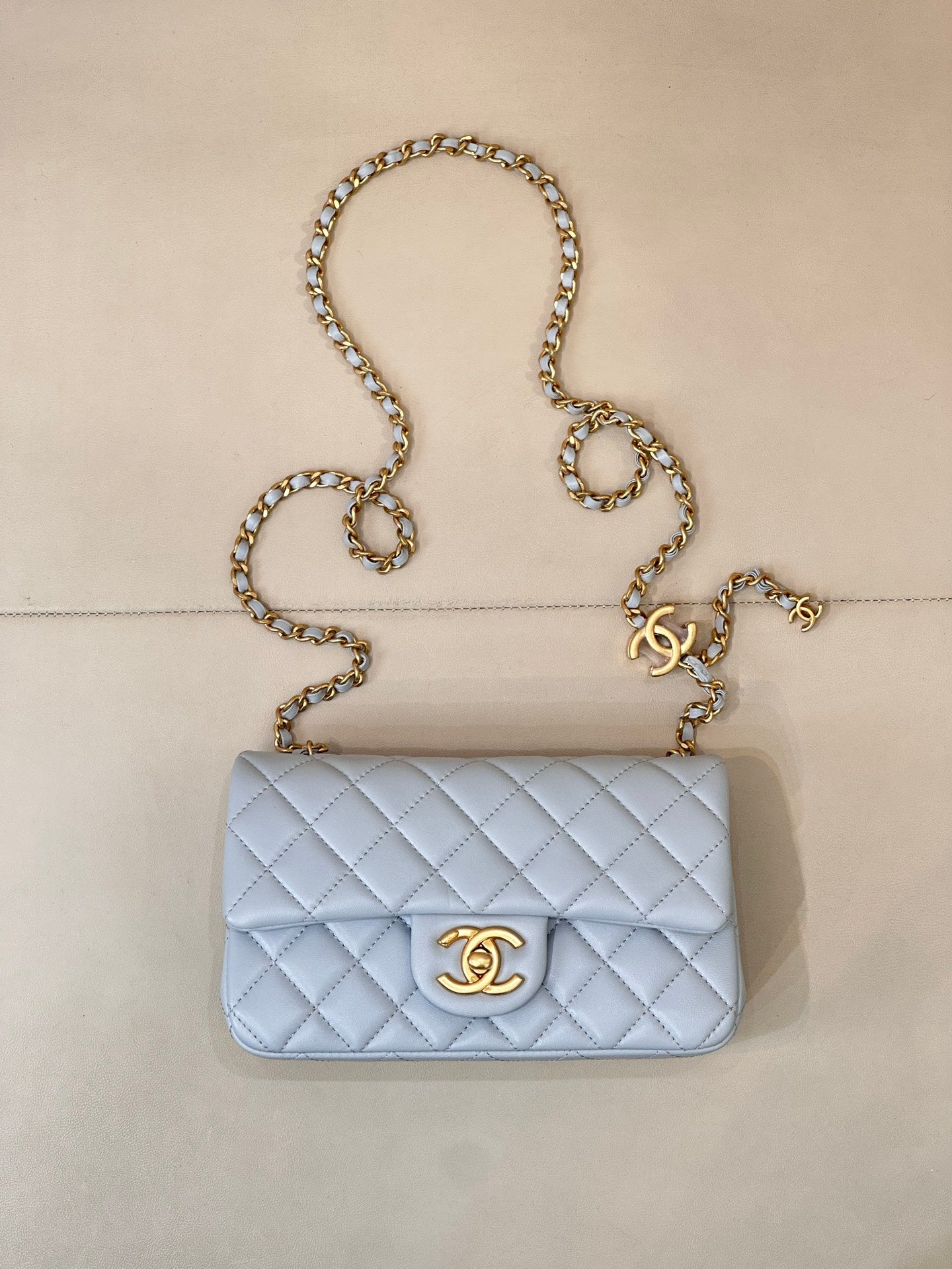 Light blue quilted flap shoulder bag with gold chain and gold logo medallion