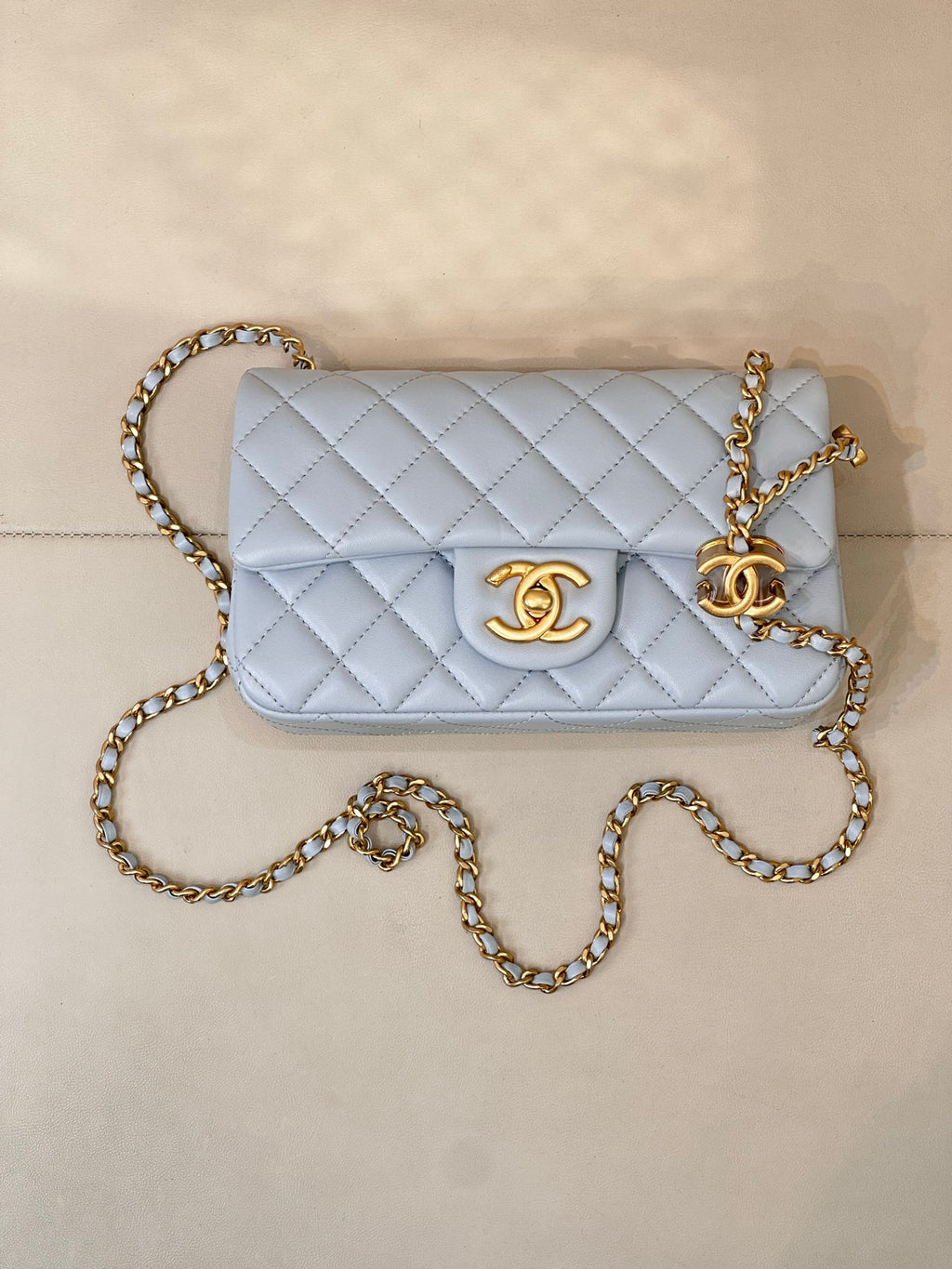 Light blue quilted flap crossbody bag with gold chain and gold logo emblem